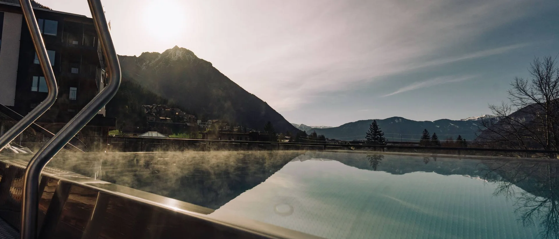 Jobs mit Herz und Qualität im Familienresort Buchau Dampfendes Schwimmbecken mit Bergblick und Sonnenuntergang im Hintergrund